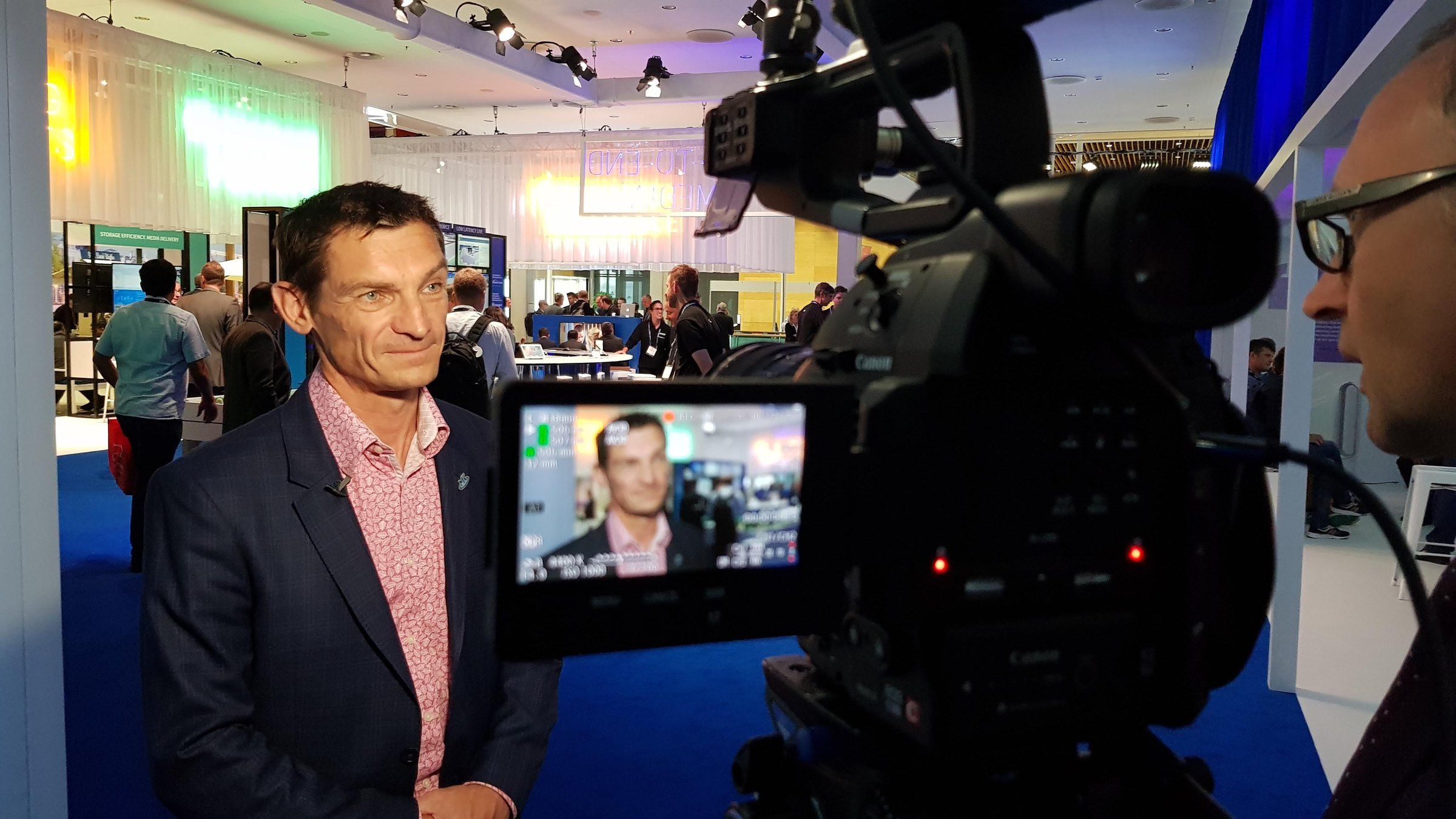 An exhibitor being interviewed on his stand, shown on the camera monitor