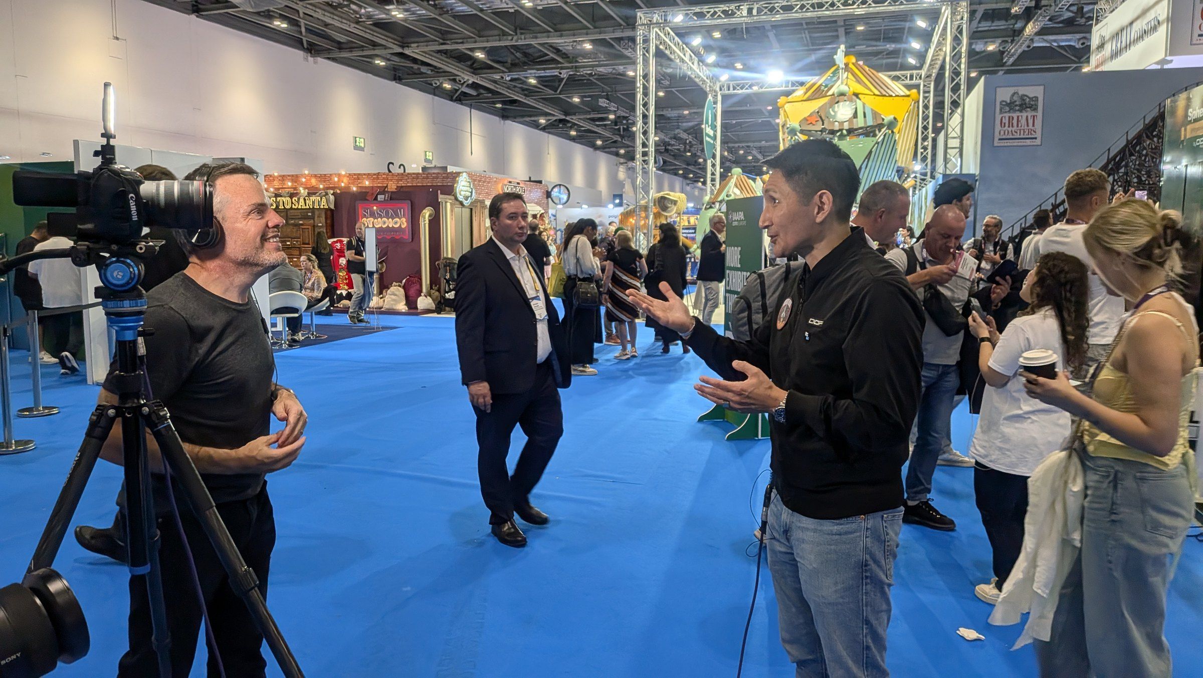Captive8 crew interviewing an exhibitor in a busy exhibition aisle