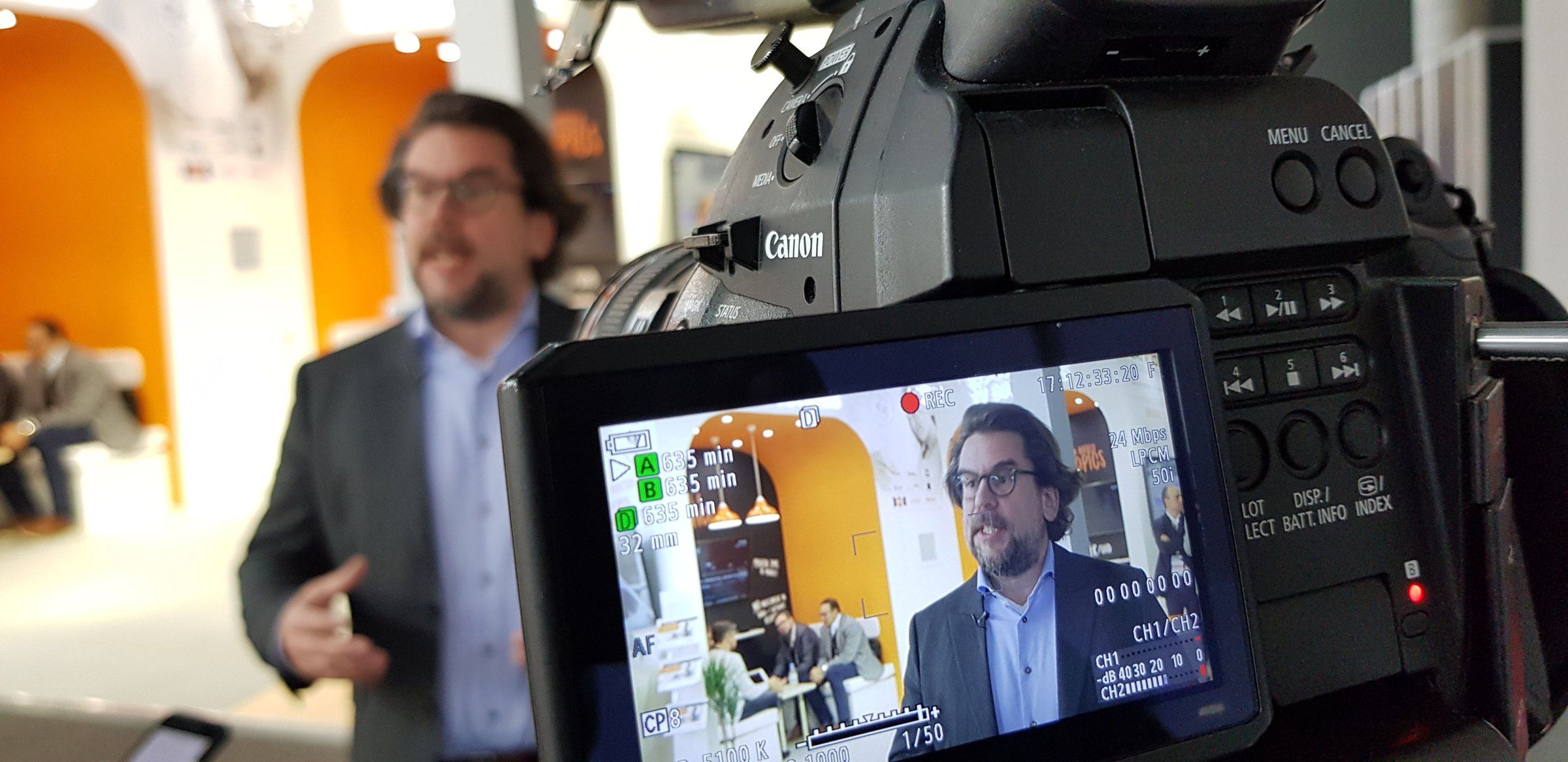 An interview on an exhibition stand, framed on the camera's monitor
